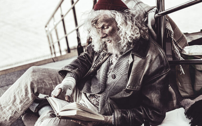 Old dirty loafer reading book that passer by giving him