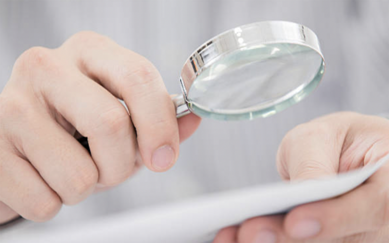 A person examining a document with a magnifying glass