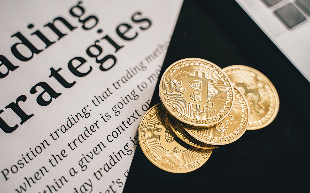 Golden Bitcoin coins placed on a trading strategies document, symbolizing the intersection of cryptocurrency, regulation, and digital legacy planning.