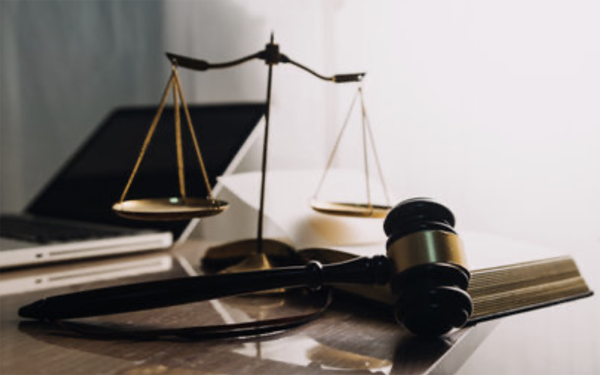 Scales of justice, judge’s gavel, and legal documents on a desk beside a laptop, symbolizing estate planning, legal trusts, and inheritance law.