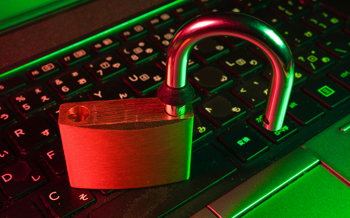An unlocked padlock on a laptop keyboard under red and green light, symbolizing cybersecurity risks and the importance of digital asset protection.